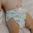 Load image into Gallery viewer, Baby wearing a Reusable Cloth Nappy – Pineapples | 2.0 | My Little Gumnut shown from the front to highlight fit and flexibility.