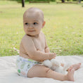 Load image into Gallery viewer, Baby wearing a Reusable Cloth Nappy – Pineapples | 2.0 | My Little Gumnut shown sitting outdoors to demonstrate comfort and fit.