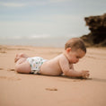 Load image into Gallery viewer, Baby playing on the beach wearing a Reusable Swim Nappy - Gumnut, perfect for water activities.