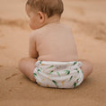 Load image into Gallery viewer, Baby wearing a Reusable Swim Nappy by My Little Gumnut, seated on the sandy beach, showcasing Australian-inspired design.