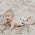 Load image into Gallery viewer, Happy baby crawling on sand wearing a Reusable Swim Nappy with flower design, perfect for beach days.