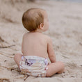 Load image into Gallery viewer, Reusable Swim Nappy - Palm Garden on a toddler sitting on the beach sand.