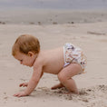 Load image into Gallery viewer, Toddler playing on the beach wearing a Reusable Swim Nappy - Palm Garden for sunny days and aquatic fun.