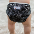 Load image into Gallery viewer, Reusable Swim Nappy in Black Flora design, perfect for beach and pool play with comfort and waste reduction.