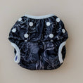 Load image into Gallery viewer, Reusable Swim Nappy in Black Flora design with floral patterns and white snaps, perfect for beach and pool days.