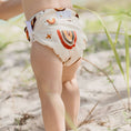 Load image into Gallery viewer, Reusable Swim Nappy in rainbow earth tones on a toddler at the beach, perfect for comfort and waste reduction.