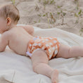 Load image into Gallery viewer, Baby wearing a Reusable Swim Nappy in Gingham (Rust) design, enjoying comfort on a sandy beach.