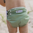 Load image into Gallery viewer, Reusable Swim Nappy - Sage on a baby, showcasing its soft design and adjustable snaps for comfort.