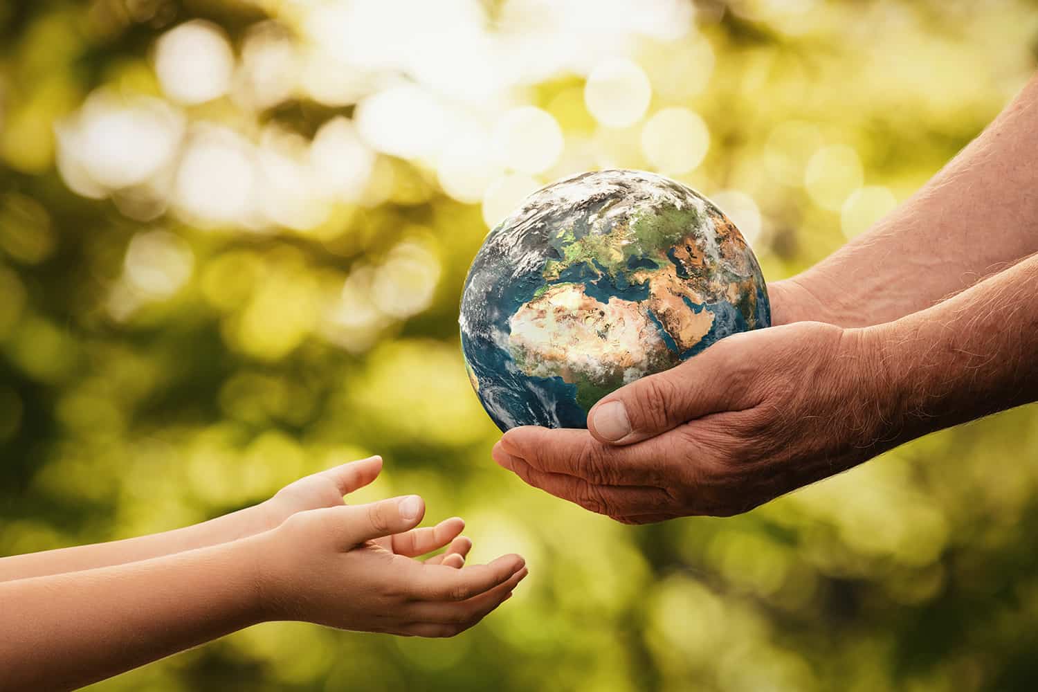 An elderly person handing a miniature earth to a young person