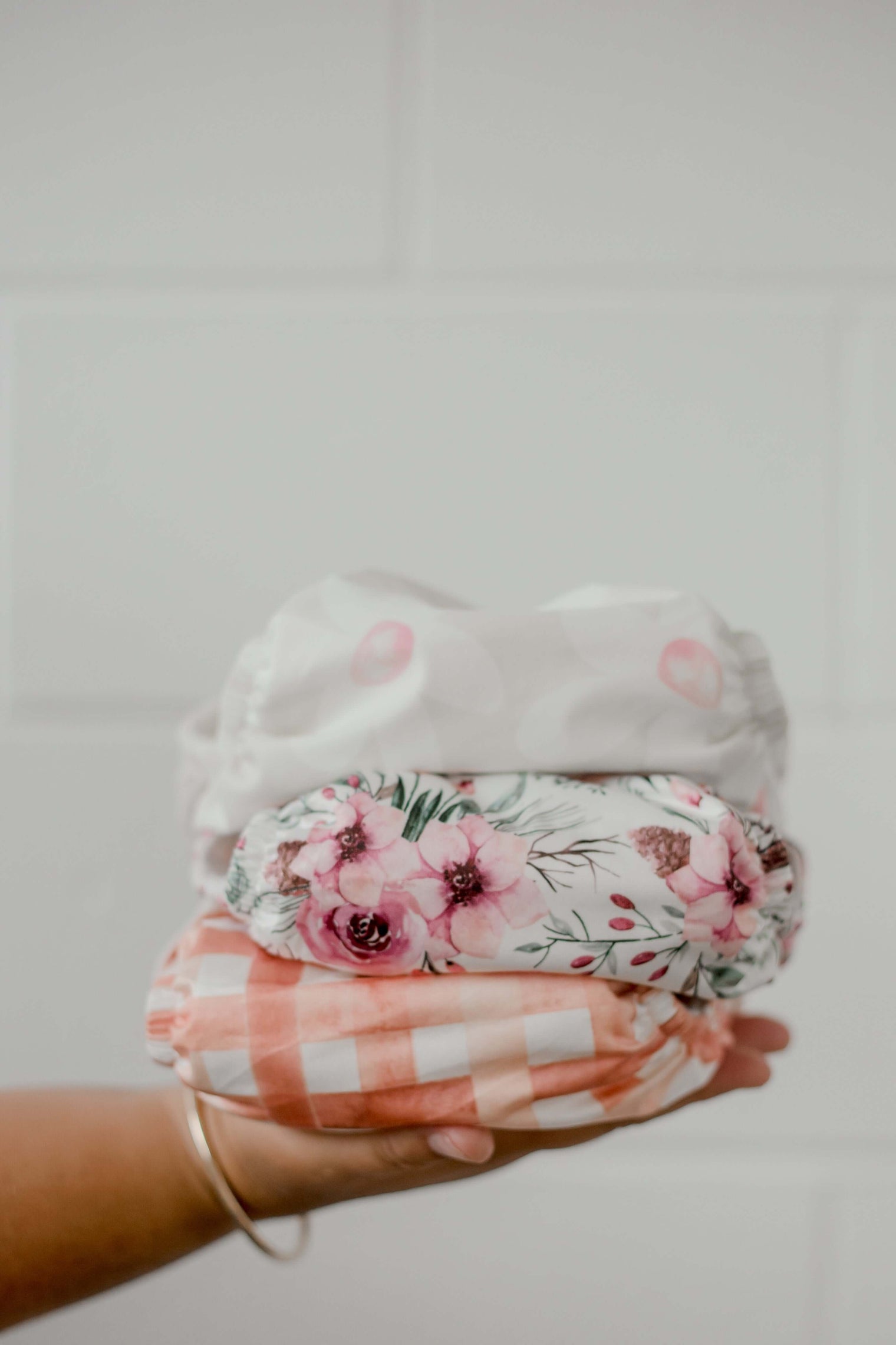 A hand holding three My Little Gumnut Cloth Nappies