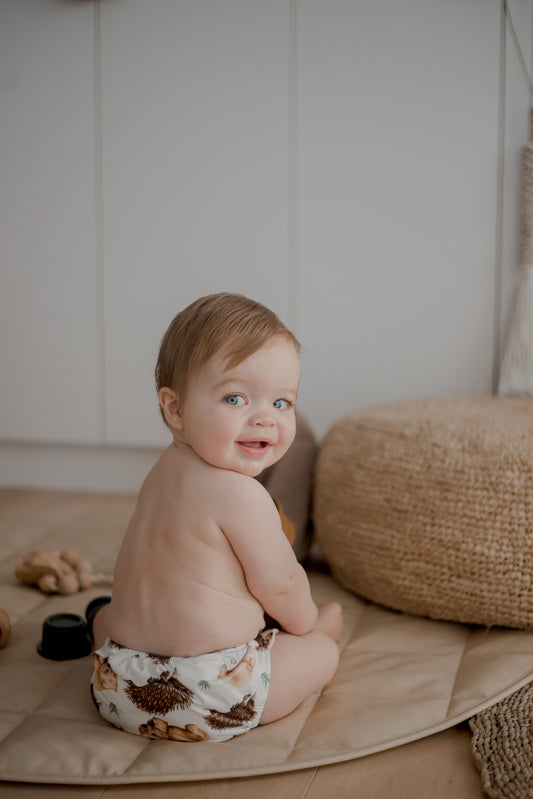 Baby with back to camera turning and smiling wearing a My Little Gumnut Cloth Nappy
