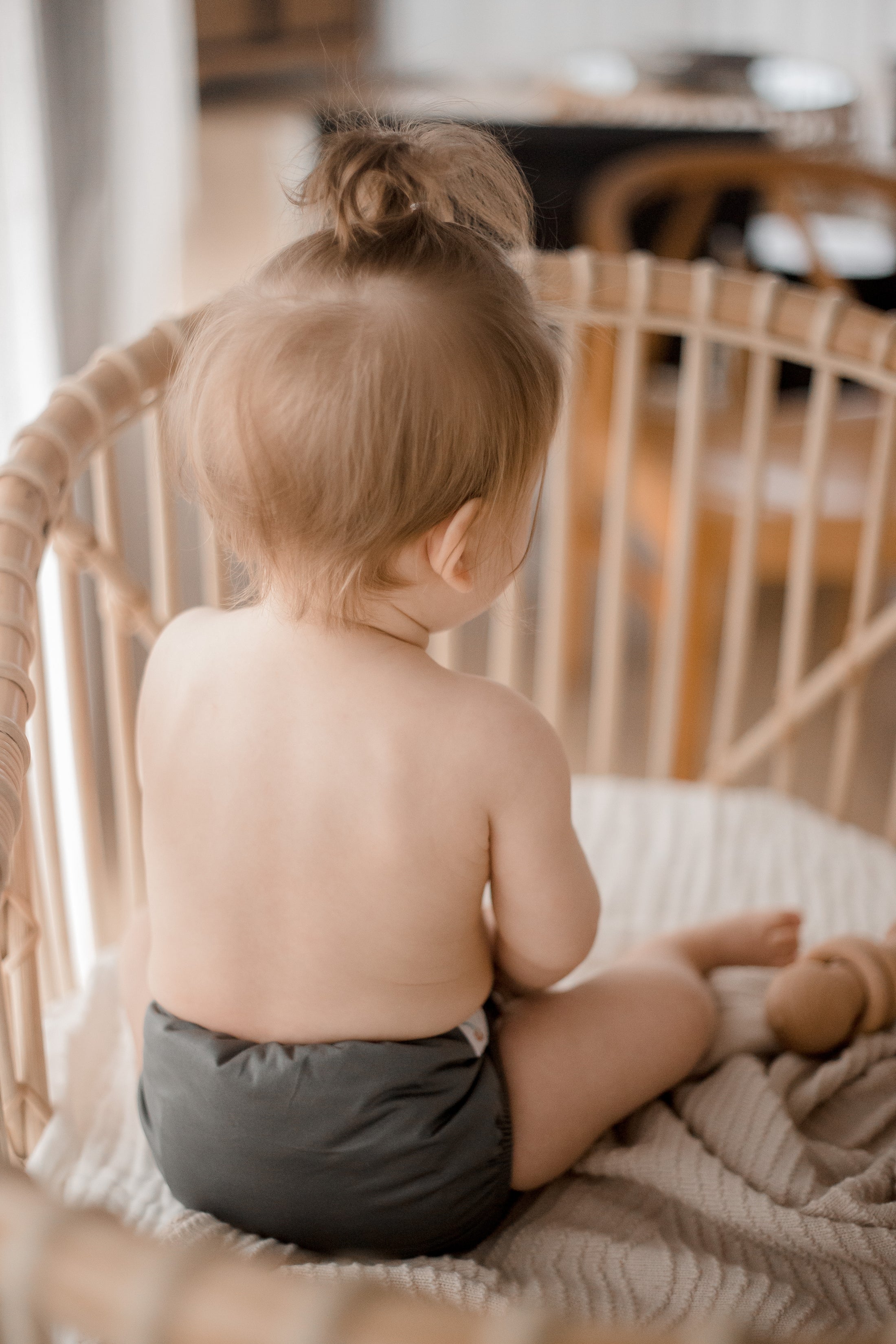 Baby sitting in a cot wearing Grey Cloth Nappy by My Little Gumnut. Australian reusable nappies. ecofriendly nappies