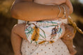 Load image into Gallery viewer,  beach baby wearing medium size reusable swim nappy. Australian artist desinged banksia flower. 
