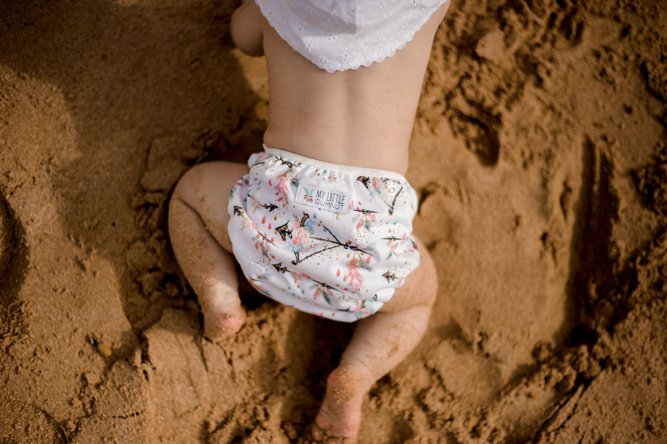 Baby wearing boho princess reusable swimming nappy at the beach. Australian designed cloth swimming nappy. My Little Gumnut.