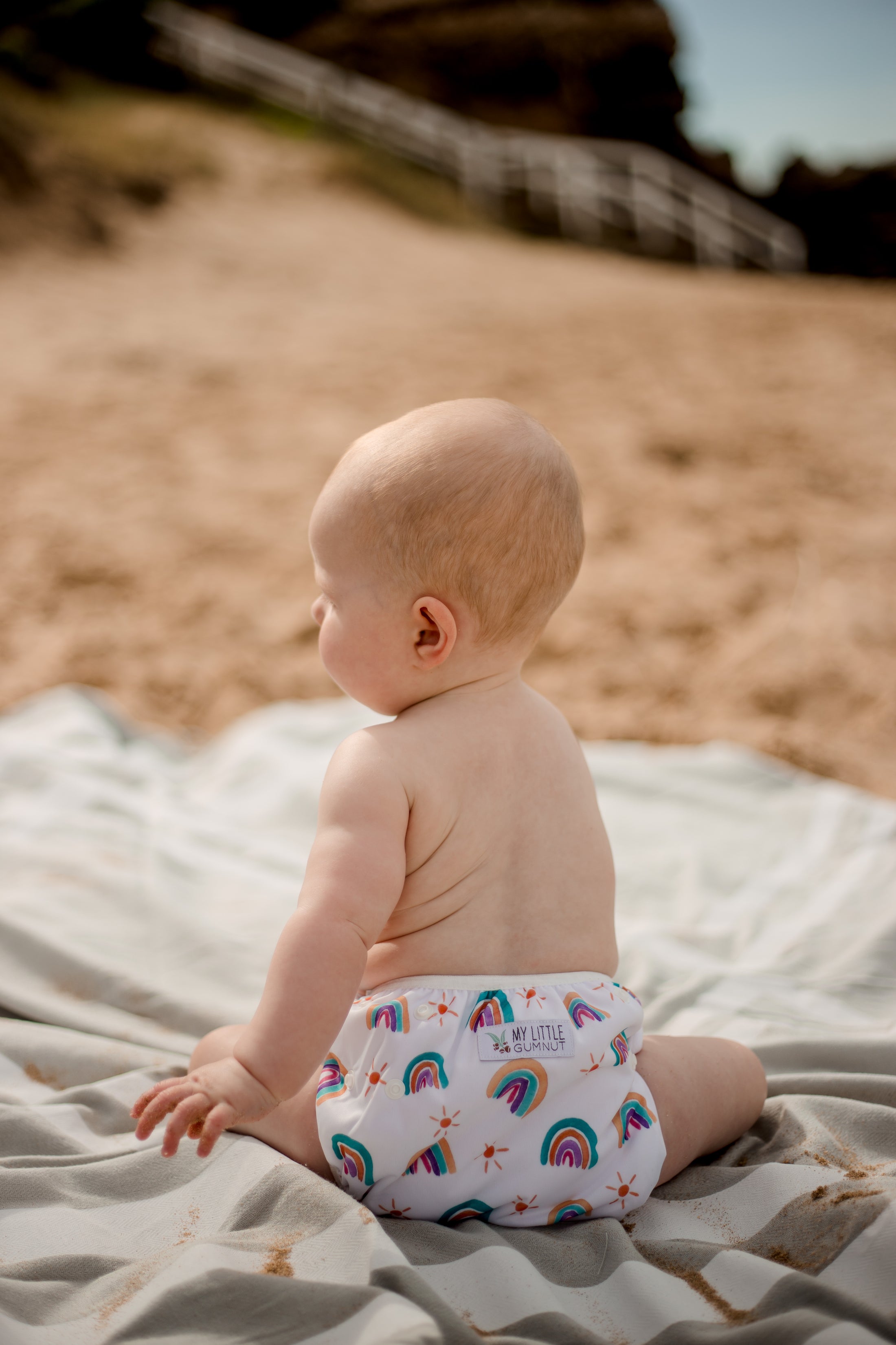 beach baby wearing  pastel rainbow swimming nappy. Australian artist designed swim nappy. My little Gumnut. 