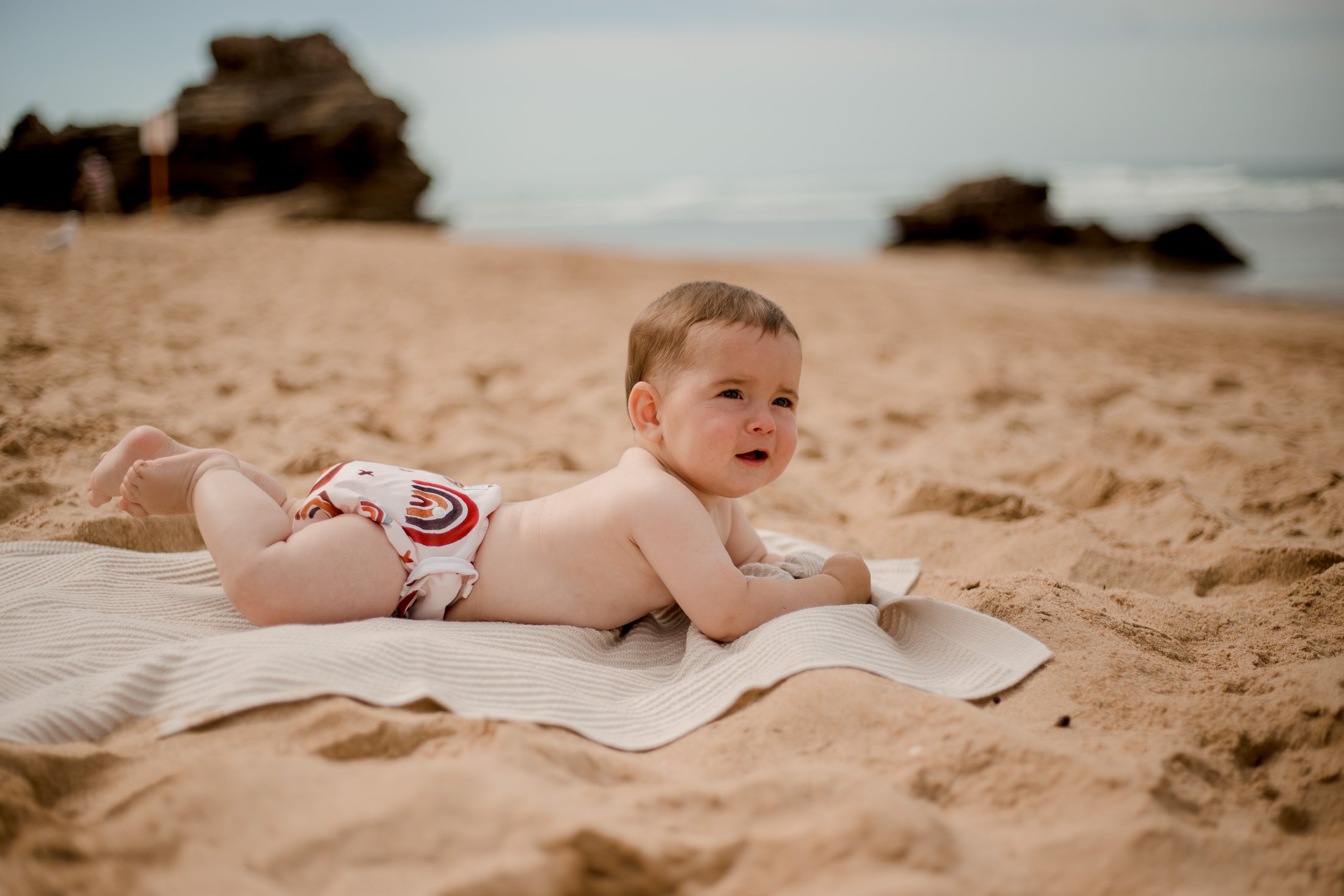Beach baby wearing Rainbow earth tones swimming nappy. Australian artists designed swim nappy. My little gumnut. 